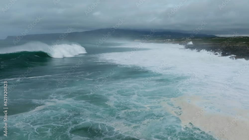 Aerial view of a mesmerising turquoise ocean with big waves and spindrift on Guincho Beach, Cascais, Portugal. Aerial view of a mesmerising turquoise ocean with big waves and spindrift on Guincho Beach, Cascais, Portugal.