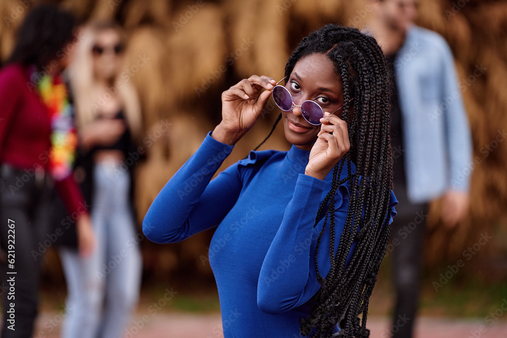African American woman with sunglasses looking at camera while posing outdoors during a party.