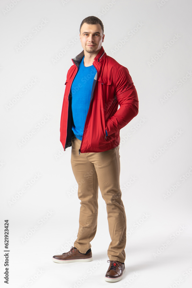Fototapeta premium A man of athletic build in a red jacket stands and holds his hands in his pockets