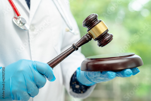 Obraz na płótnie Doctor holding judge gavel, forensic medicine, medical law and crime justice concept