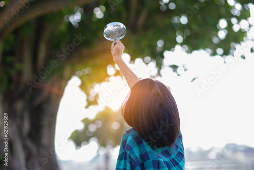 Asian little girl is using magnifying glass to play in the park.SSTKHome