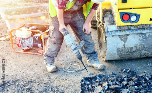 Builder breaking asphalt with electric breaker