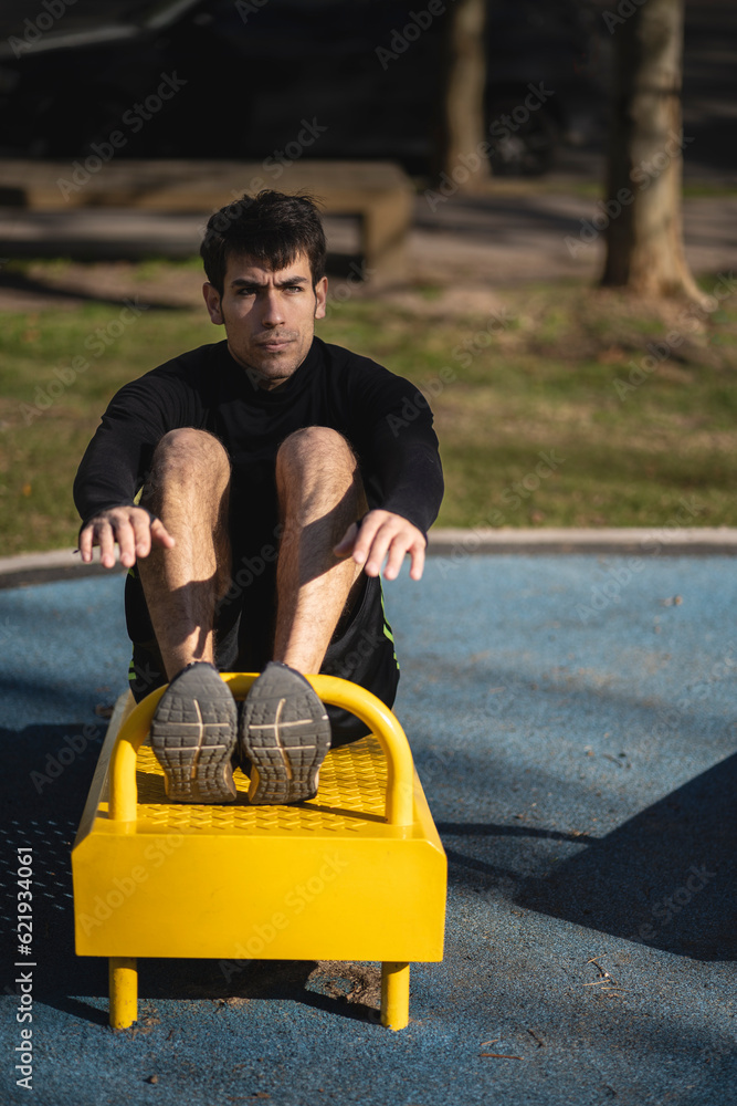 Attractive man doing sit-ups in the park. Attractive man doing sit-ups in the park.