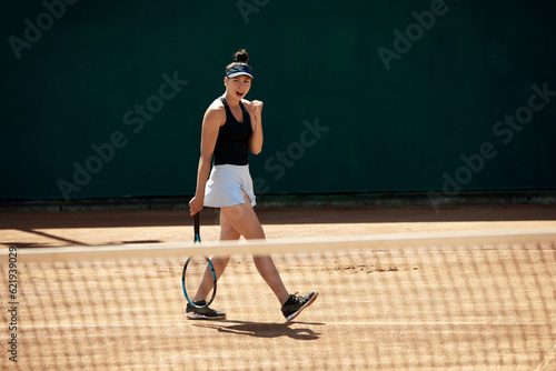Dynamic image of young woman, professional tennis player in motion during game outside, at open air stadium, court. Winning goal. Concept of sport, hobby, active lifestyle, health, strength, ad © master1305