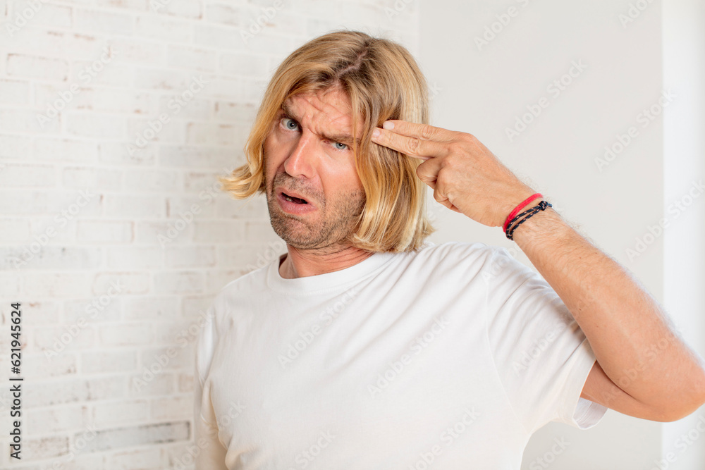 young blond adult man looking unhappy and stressed, suicide gesture making gun sign with hand, pointing to head young blond adult man looking unhappy and stressed, suicide gesture making gun sign with hand, pointing to head