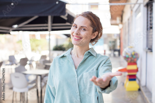 pretty young woman smiling, looking happy, confident and friendly, offering a handshake to close a deal, cooperating