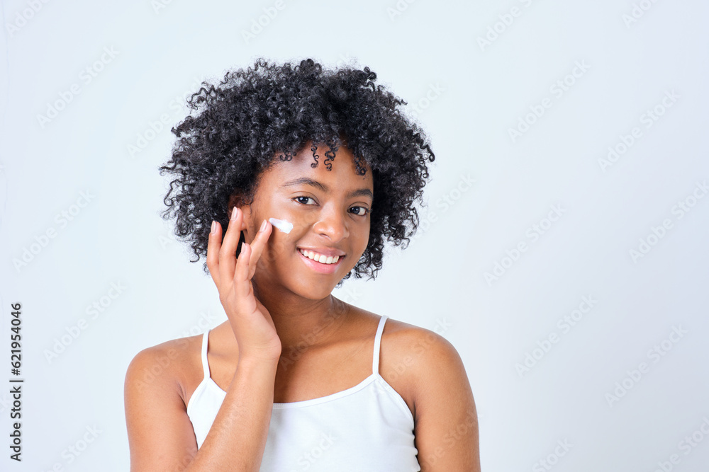 smiling african american young girl giving cream on her face with hand on white background