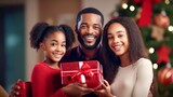 portrait black happy family with christmas outfit holding red gift box with a defocused christmas tree background