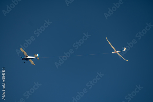 Propeller plane pulling a glider on a rope against the blue sky