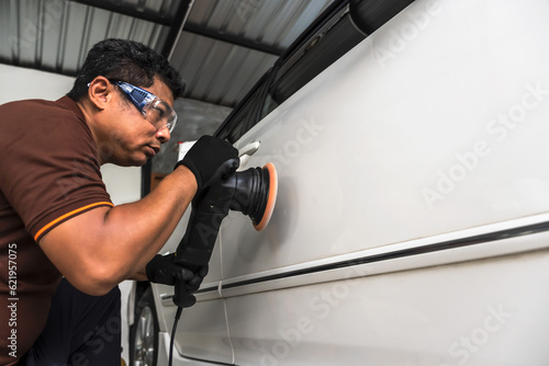 Car cleaning man with safety goggles using orbital polishing polish white car in Car Care service