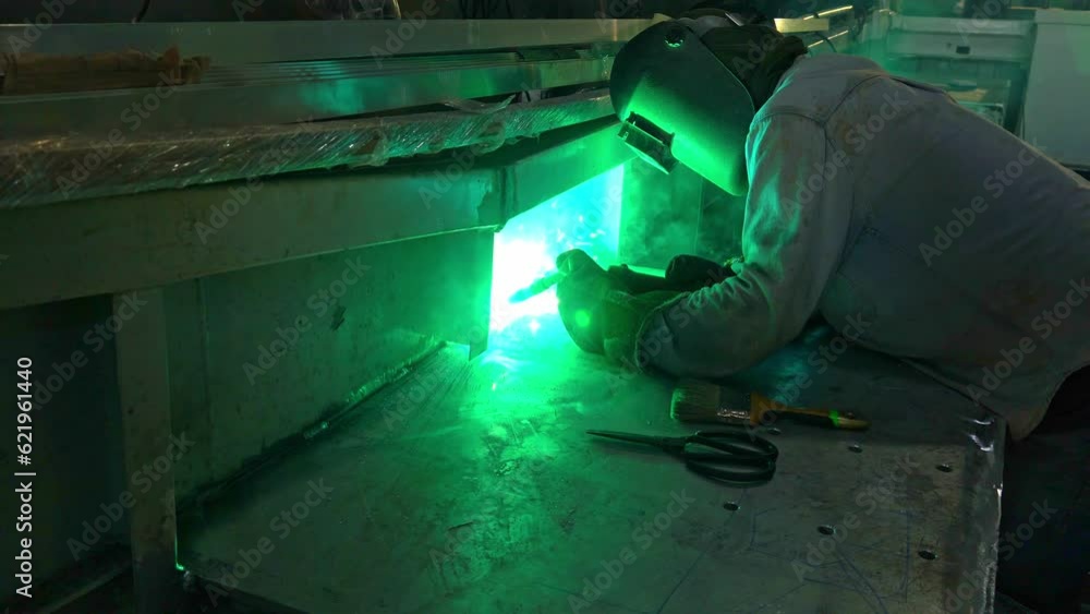.Workers are welding metal in a shipyard with spacial welding rods