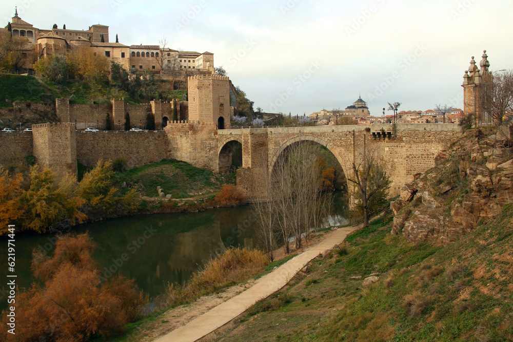 View of the historic part of the city with the Alcantara Bridge and Gate and the Tagus River in the foreground in the city of Toledo, near Madrid, Spain