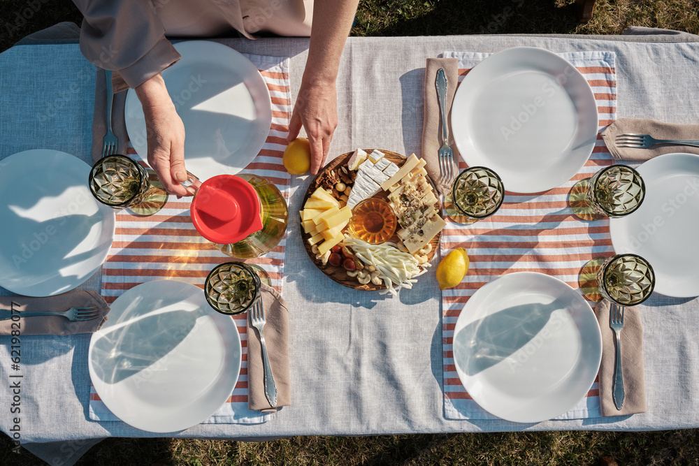 Close-up view of the table setting in the back of the house, preparation for dinner in the backyard of the house by  woman, the woman are setting the table outdoors