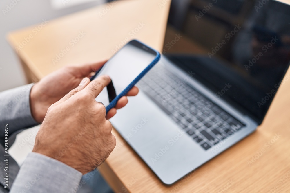 Young hispanic man using smartphone and laptop at office Young hispanic man using smartphone and laptop at office