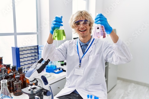 Young blond man scientist holding test tubes at laboratory
