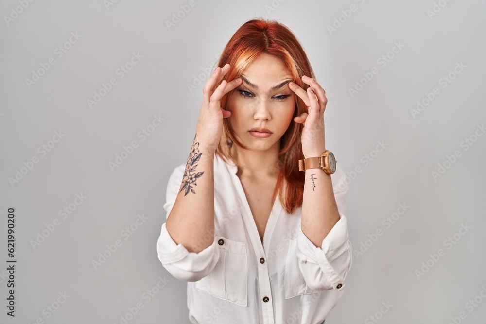 Young caucasian woman standing over isolated background trying to open eyes with fingers, sleepy and tired for morning fatigue