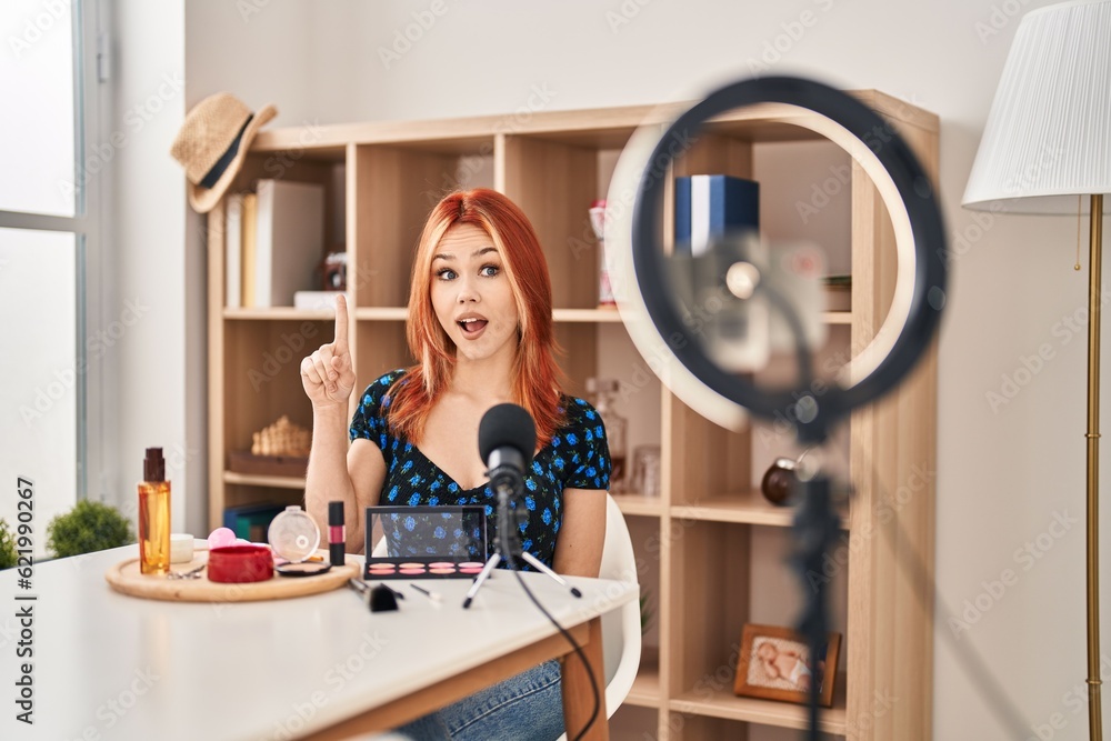 Young caucasian woman applying make up doing tutorial pointing finger up with successful idea. exited and happy. number one. Young caucasian woman applying make up doing tutorial pointing finger up with successful idea. exited and happy. number one.