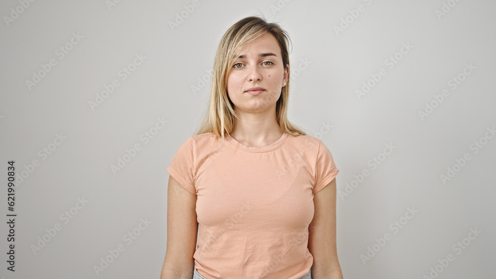 Young blonde woman standing with serious expression over isolated white background Young blonde woman standing with serious expression over isolated white background