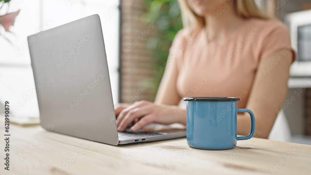 Young blonde woman using laptop sitting on table at dinning room Young blonde woman using laptop sitting on table at dinning room