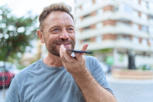 Middle age man smiling confident talking on the smartphone at street