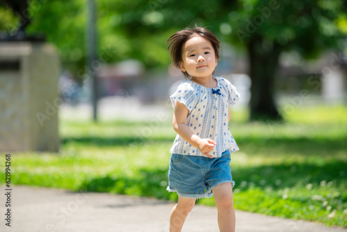 新緑の公園で遊ぶ3歳の女の子