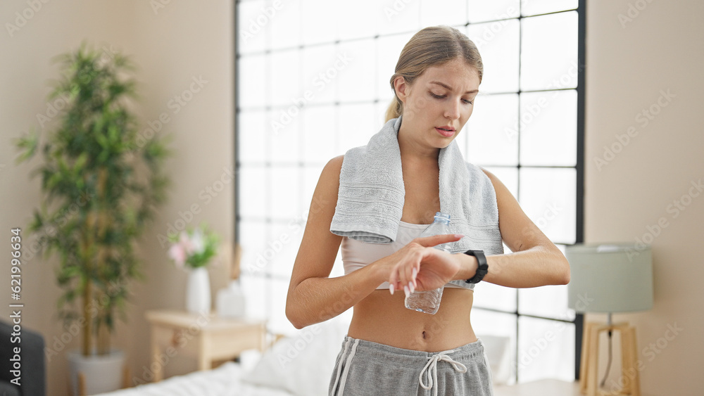 Young blonde woman wearing sportswear looking watch at bedroom Young blonde woman wearing sportswear looking watch at bedroom