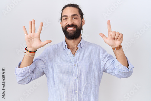 Hispanic man with beard wearing casual shirt showing and pointing up with fingers number seven while smiling confident and happy. © Krakenimages.com