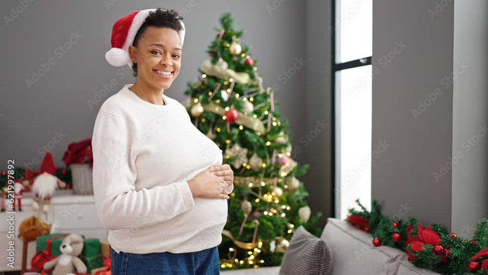 Young pregnant woman touching belly celebrating christmas at home Young pregnant woman touching belly celebrating christmas at home