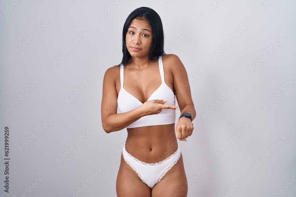 Hispanic woman wearing lingerie in hurry pointing to watch time, impatience, upset and angry for deadline delay Hispanic woman wearing lingerie in hurry pointing to watch time, impatience, upset and angry for deadline delay