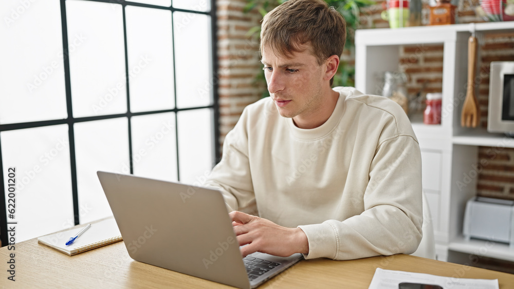 Young caucasian man using laptop sitting on table at dinning room Young caucasian man using laptop sitting on table at dinning room