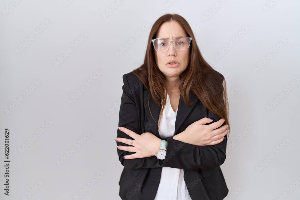 Beautiful brunette woman wearing business jacket and glasses shaking and freezing for winter cold with sad and shock expression on face Beautiful brunette woman wearing business jacket and glasses shaking and freezing for winter cold with sad and shock expression on face