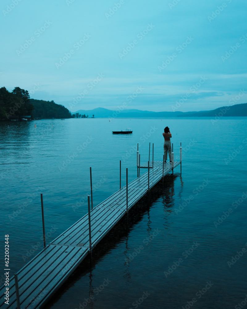 Person on a dock on a gloomy blue evening on Lake George in Silver Bay, New York