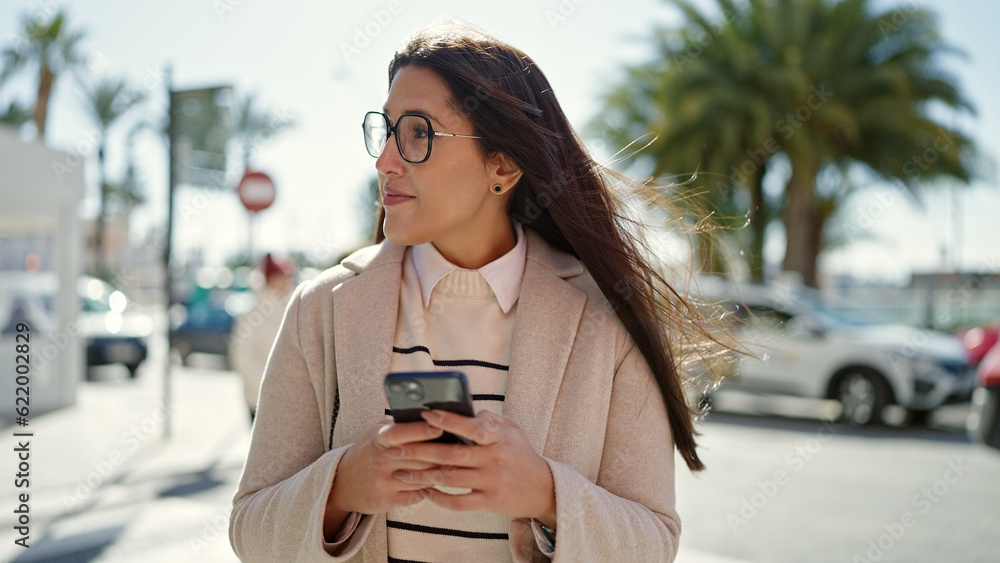 Obraz premium Young beautiful hispanic woman using smartphone with serious expression at street
