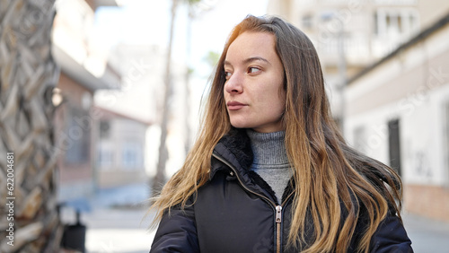 Young caucasian woman looking to the side with serious expression at street