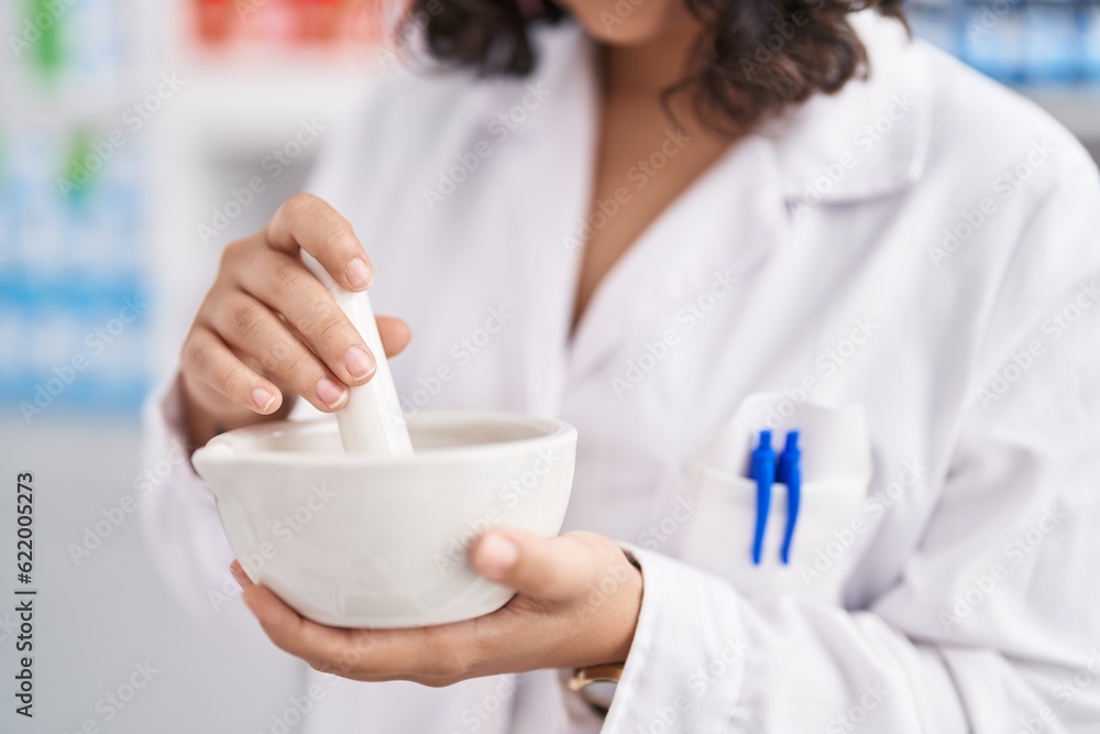 Young woman pharmacist mixing medicine at pharmacy