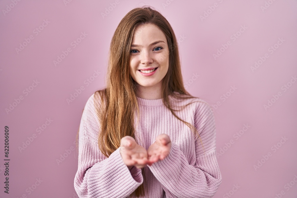 Young caucasian woman standing over pink background smiling with hands palms together receiving or giving gesture. hold and protection Young caucasian woman standing over pink background smiling with hands palms together receiving or giving gesture. hold and protection