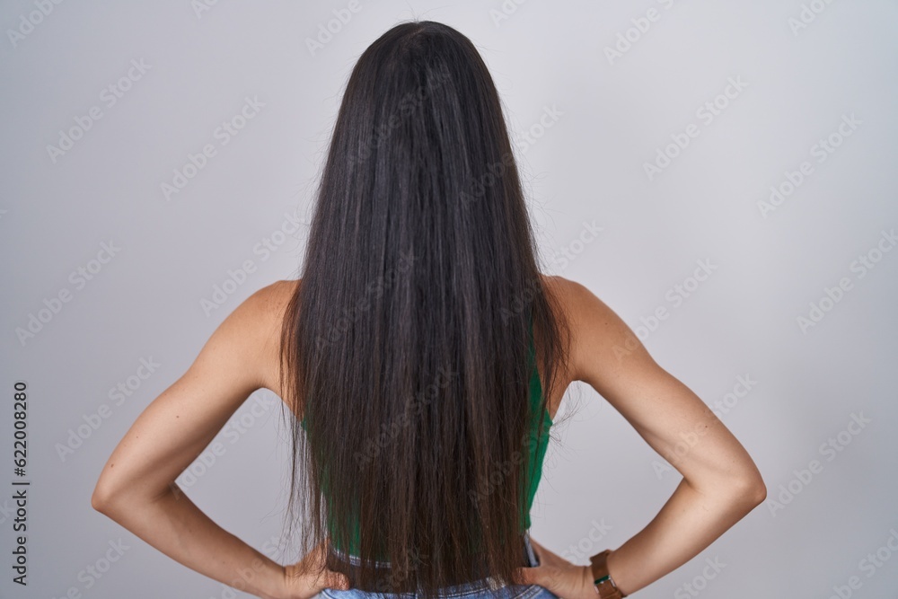 Naklejka premium Young woman standing over isolated background standing backwards looking away with arms on body