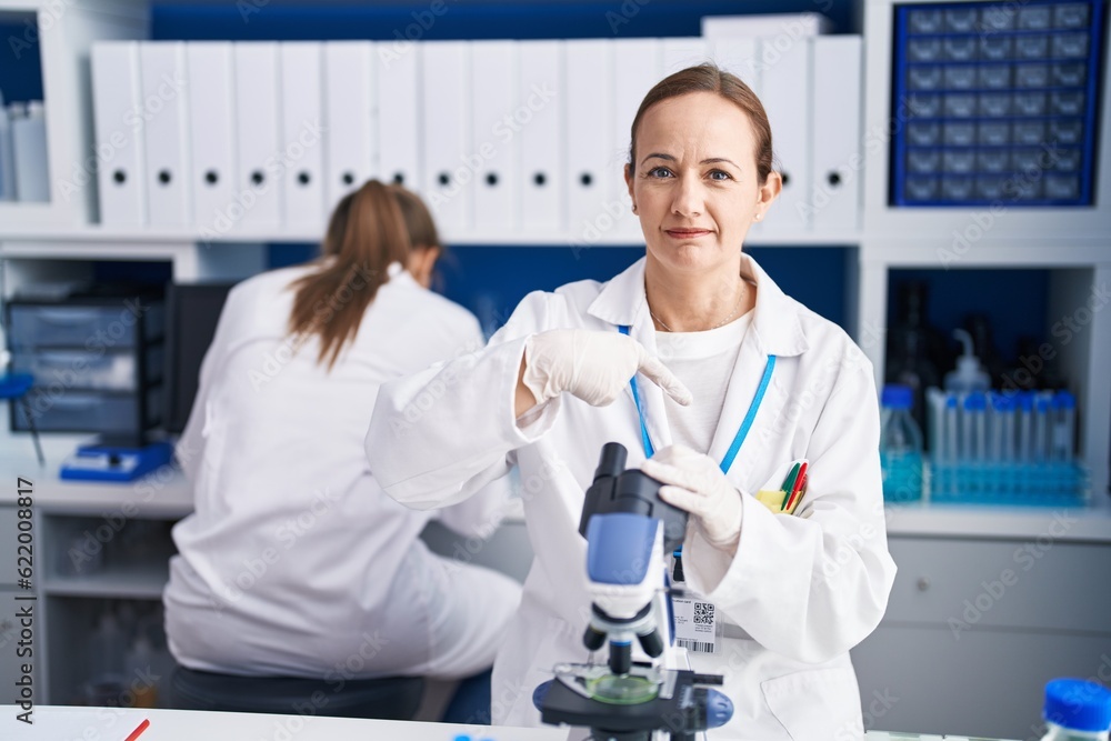 Blonde woman working on cruelty free laboratory pointing finger to one self smiling happy and proud Blonde woman working on cruelty free laboratory pointing finger to one self smiling happy and proud