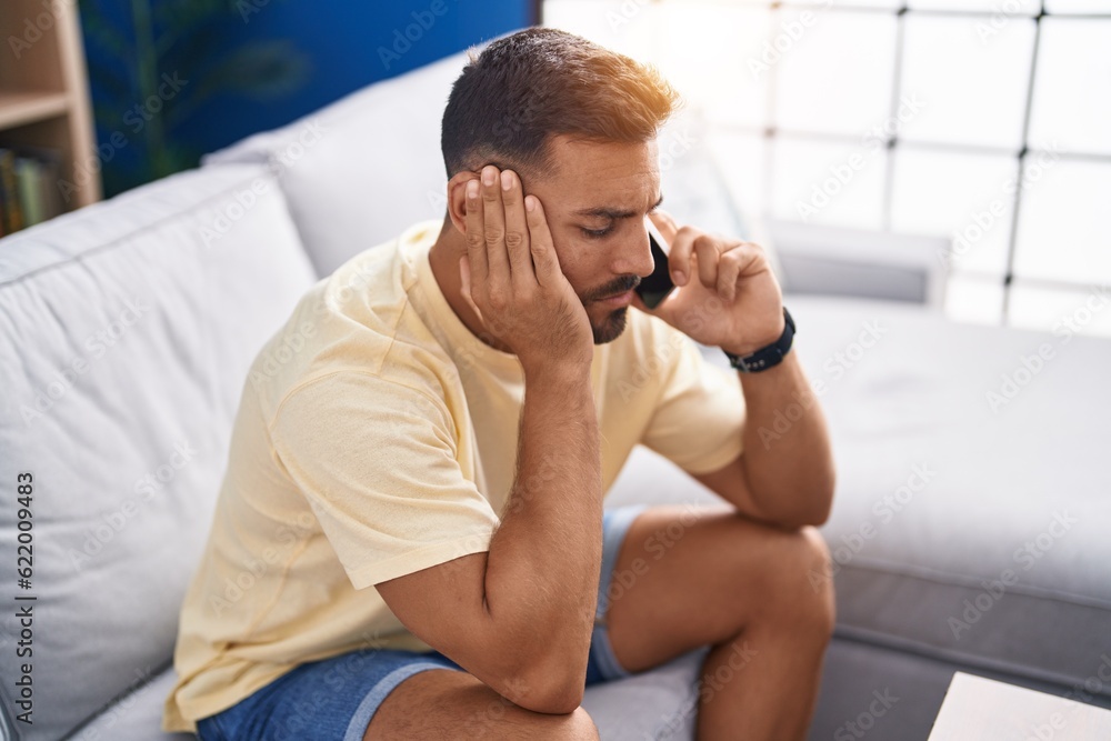 Young hispanic man talking on smartphone with worried expression at home Young hispanic man talking on smartphone with worried expression at home