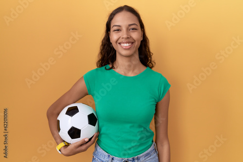 Young hispanic woman holding ball with a happy and cool smile on face. lucky person. © Krakenimages.com