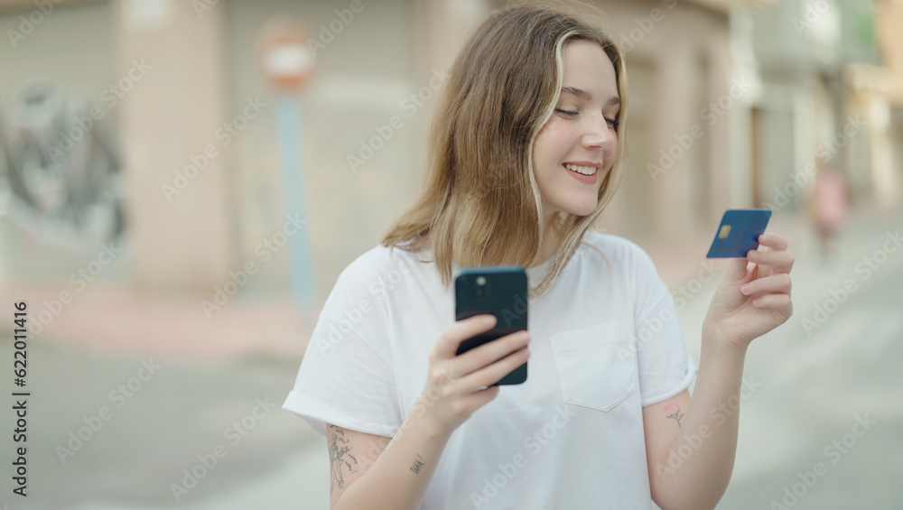 Young caucasian woman using smartphone and credit card at street