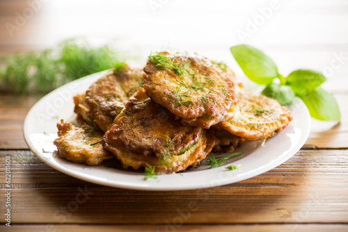 zucchini fried in circles in batter with herbs, in a plate .