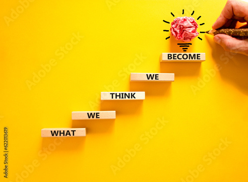 We become or think symbol. Concept word What we think We become on wooden block. Beautiful yellow table yellow background. Businessman hand. Business we become or think concept. Copy space.