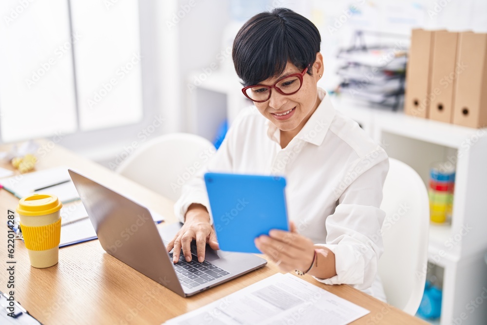Middle age chinese woman business worker using touchpad and laptop at office Middle age chinese woman business worker using touchpad and laptop at office
