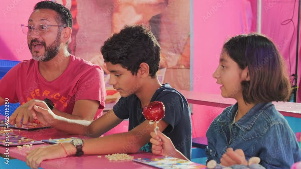 Single father and his children play Loteria, a board game.