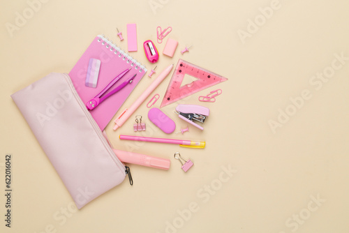 Pink pencil case with school stationery on color backgroung, top view