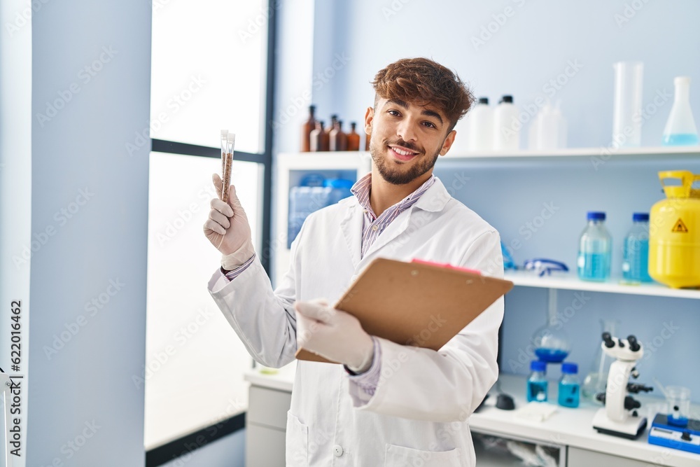 Young arab man scientist holding test tube and clipboard at laboratory Young arab man scientist holding test tube and clipboard at laboratory