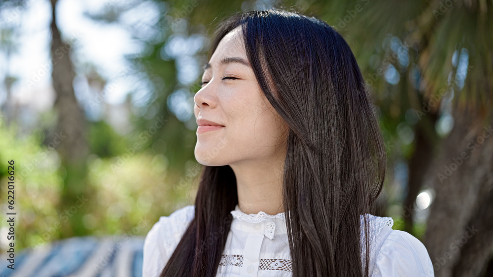 Young chinese woman breathing with closed eyes at park