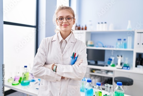 Fototapeta Naklejka Na Ścianę i Meble -  Young blonde woman scientist smiling confident standing with arms crossed gesture at laboratory