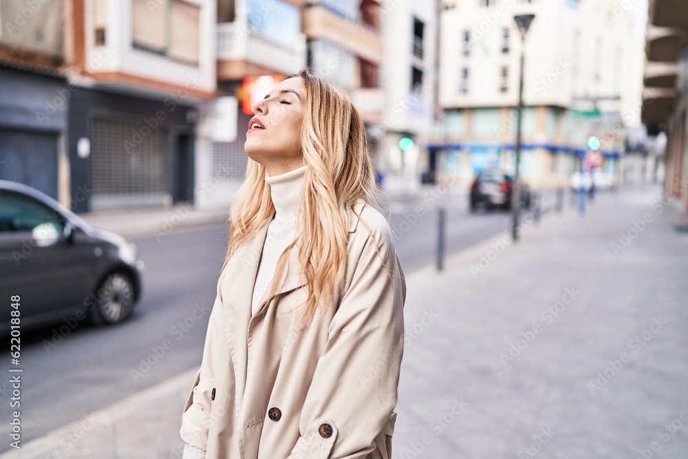 Fototapeta premium Young blonde woman standing with unhappy expression at street